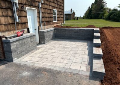 Patio installation featuring gray pavers and stone seating area, enhancing outdoor space for relaxation and entertainment, showcasing McIsaac Lawncare's craftsmanship.