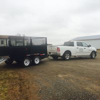 White pickup truck towing a black trailer on a gravel driveway, representing McIsaac Lawncare and Landscaping Ltd.'s landscaping and lawn care services.