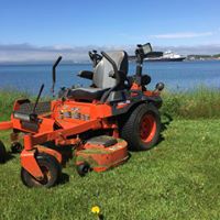 Lawn care equipment on a grassy area near water, showcasing McIsaac Lawncare's landscaping tools for outdoor transformations.