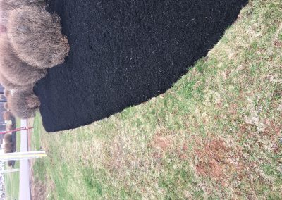 Freshly laid black mulch contrasting with green grass in a landscaped garden, showcasing McIsaac Lawncare's expertise in outdoor transformations.
