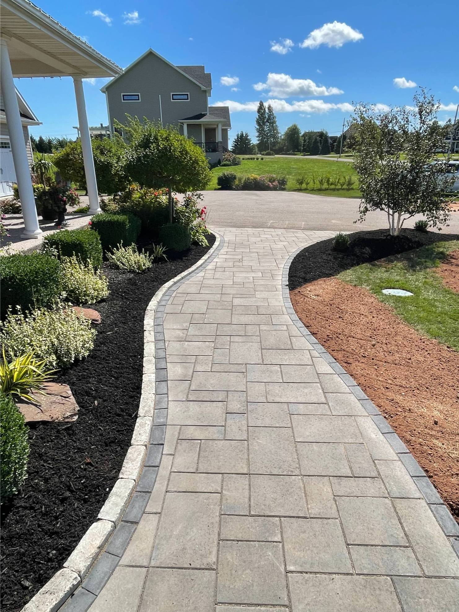 Curved stone walkway leading through landscaped garden, showcasing durable pavers and surrounding greenery, enhancing outdoor curb appeal for residential properties.