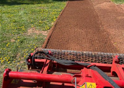 Red landscaping equipment smoothing soil in a backyard, showcasing preparation for a new outdoor space transformation by McIsaac Lawncare.