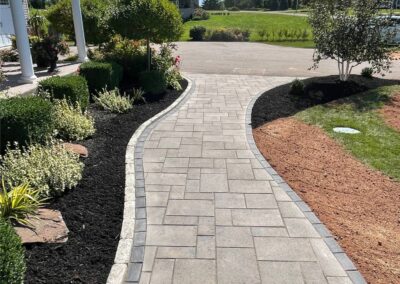 Curved stone pathway bordered by lush greenery and mulch, showcasing McIsaac Lawncare's landscaping craftsmanship and outdoor transformation capabilities.