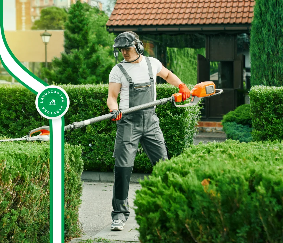 Landscaper trimming hedges with electric trimmer in residential garden, showcasing professional landscaping services by McIsaac Lawncare and Landscaping Ltd.