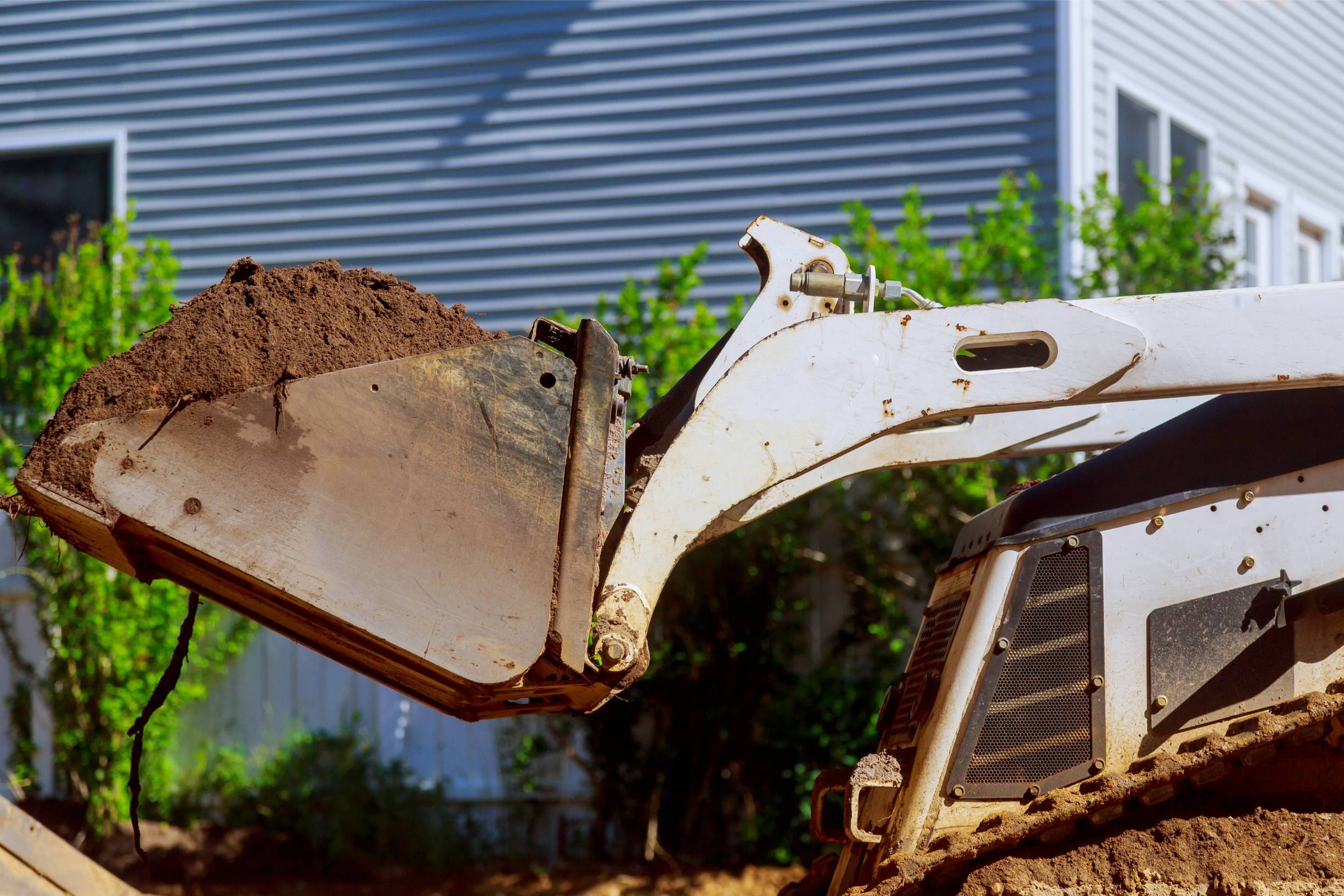 Skid steer loader lifting soil, showcasing excavation capabilities for grading and site preparation services.