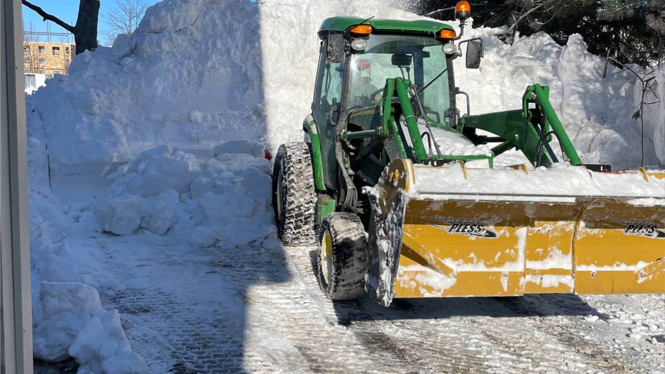 Commercial snow removal equipment clearing a snow-covered driveway, highlighting effective snow management for safety and accessibility.