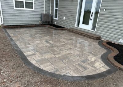 Patio with decorative pavers and curved edging, showcasing quality craftsmanship in landscaping by McIsaac Lawncare.