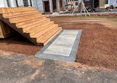 Outdoor landscaping project featuring wooden steps leading to a newly installed stone pathway, showcasing quality craftsmanship and transformation of the backyard space.