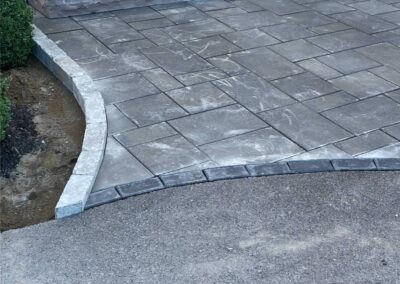 Paved patio with curved stone border showcasing quality craftsmanship in landscaping by McIsaac Lawncare.