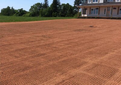 Freshly prepared lawn area with textured soil, showcasing potential for landscaping transformation, adjacent to a modern home.