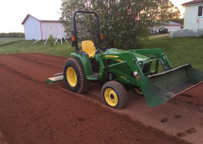 John Deere tractor preparing soil for landscaping project in residential backyard.