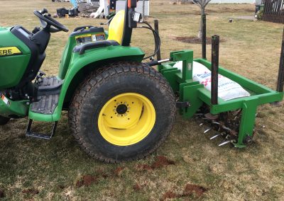 John Deere tractor with tiller attachment, showcasing lawn care equipment used for landscaping projects and outdoor transformations.